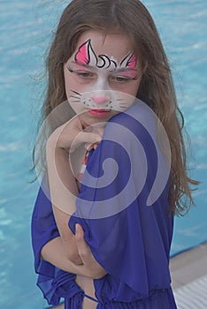 A lovely little girl with the paint on her face. Girl with a painted cat on her face. Children of the Z-generation