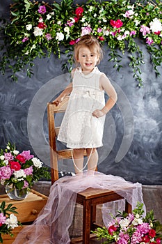 Lovely little girl plays against the flowers background. Portrait of the pretty smiling little girl