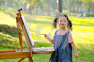 Lovely little girl show happy smile and enjoy with painting in the garden with morning light