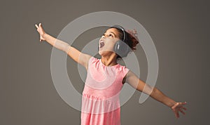 Lovely little girl is singing in headphones