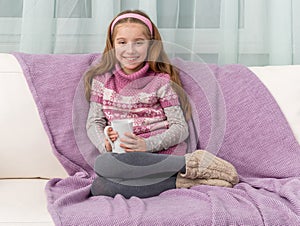 Lovely little girl on a sofa with warm blanket