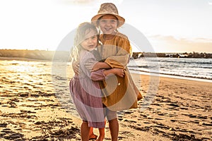 Lovely little sisters having fun at the beach, sunset summer time. A lot of copy space. Travel
