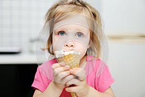 Lovely little toddler girl eats ice-cream