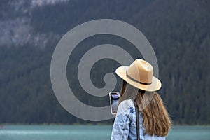 A lovely long hair lady takes pictures of Lake Louise