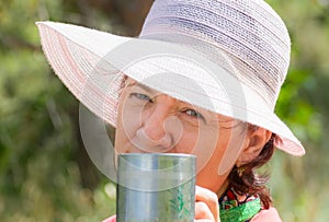 Lovely mature brunette cts in a lounge chair drinking coffee on a summer day.