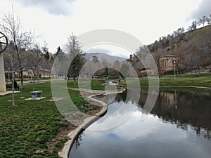 Memory Grove Park views of Waterfalls and streams leading into a small pond or lake surrounded by walking paths and trees in Salt