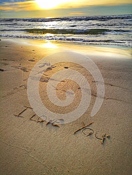 A love message I love you written on the sandy beach.