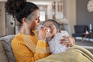 Lovely mother embracing daughter making inhalation with a nebulizer