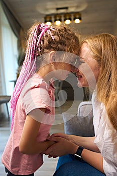 Lovely mother and little daughter with pink braids rubbing nose to nose