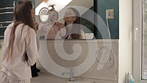 Lovely mother with little family brushing teeth in bathroom