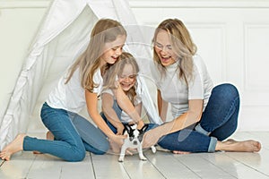 Lovely mother and two daughter and little dog pet indoor. Happy family portrait