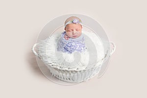 Lovely newborn baby girl wrapped in a purple cocoon