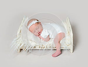 Lovely newborn baby sleeping on crib with leg on the floor