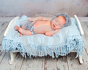 Lovely newborn boy sleeping on little bed with blue diaper