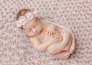 Lovely newborn curled up asleep, wrapped in pink diaper