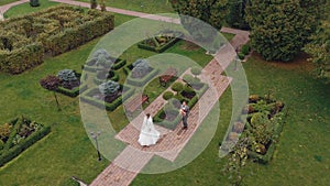 Lovely newlyweds bride meeting groom with bouquet in park making kiss, wedding couple, aerial view