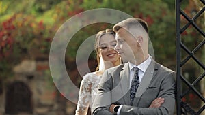 Lovely newlyweds caucasian bride embracing groom in park making kiss, wedding couple family hugging