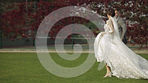 Lovely newlyweds caucasian bride groom running in park, holding hands, wedding couple family