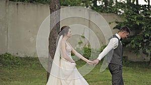 Lovely newlyweds caucasian bride groom walking in park, holding hands, wedding couple family