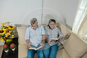 A lovely older couple relaxing on the couch, reading a book