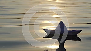 A lovely paper boat floats in a forest lake at sunset in slo-mo