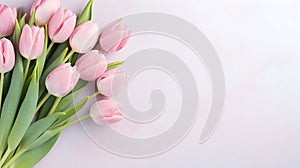 Lovely pastel pink tulips bunch, floral border at light stone background, top view. Layout for springtime holidays.