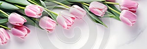 Lovely pastel pink tulips bunch, floral border at light stone background, top view. Layout for springtime holidays.