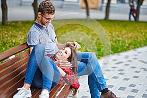 Lovely portrait of a young couple. They are sitting on the bench, embracing and kissing