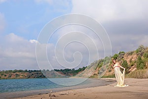 Lovely pregnant girl against a background of water and sky in a cloth.