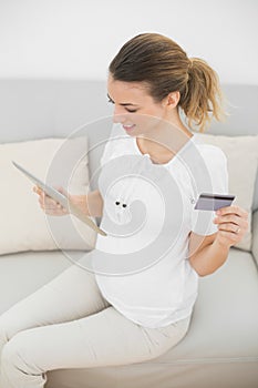 Lovely pregnant woman home shopping with her tablet