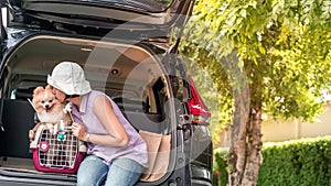 Lovely puppy pomeranian dog with Asia women owner at the back of suv car on travel tip and copy space