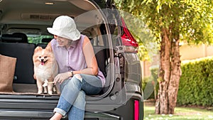 Lovely puppy pomeranian dog with Asia women owner at the back of suv car on travel tip and copy space