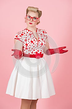 Lovely puzzled caucasian female with surprised expression with hands and glassed poses against pastel pink studio background photo