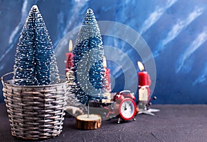 Lovely red and blue Christmas decorations. Blue decorative trees in grey rustic bucket, red clock and burning candles