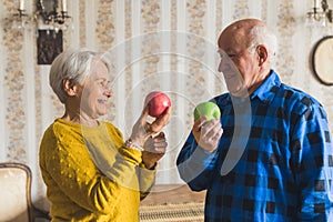 lovely retired couple holding apples in the living room healthy eating concept medium shot indoor