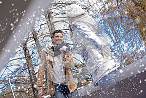 Lovely romantic Caucasion couple having fun and enjoying snowfall in winter park