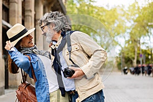 Lovely senior couple of tourist enjoying vacation together in city street