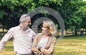 Lovely senior elderly smiling couple man and woman look at each other in romantic moment in the park. Warm heart marriage and love