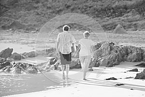 Lovely senior mature couple on their 60s or 70s retired walking happy and relaxed on beach sea shore in romantic aging together