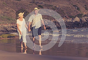 Lovely senior mature couple on their 60s or 70s retired walking happy and relaxed on beach sea shore in romantic aging together