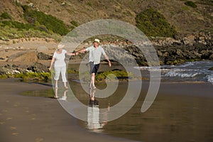 Lovely senior mature couple on their 60s or 70s retired walking happy and relaxed on beach sea shore in romantic aging together