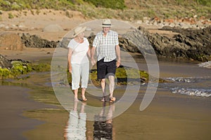 Lovely senior mature couple on their 60s or 70s retired walking happy and relaxed on beach sea shore in romantic aging together