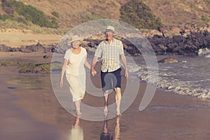 Lovely senior mature couple on their 60s or 70s retired walking happy and relaxed on beach sea shore in romantic aging together