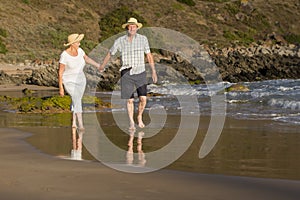 Lovely senior mature couple on their 60s or 70s retired walking happy and relaxed on beach sea shore in romantic aging together