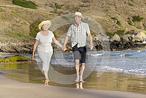 Lovely senior mature couple on their 60s or 70s retired walking happy and relaxed on beach sea shore in romantic aging together