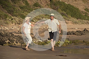 Lovely senior mature couple on their 60s or 70s retired walking happy and relaxed on beach sea shore in romantic aging together