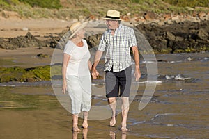 Lovely senior mature couple on their 60s or 70s retired walking happy and relaxed on beach sea shore in romantic aging together