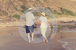 Lovely senior mature couple on their 60s or 70s retired walking happy and relaxed on beach sea shore in romantic aging together