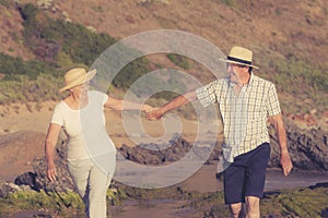 Lovely senior mature couple on their 60s or 70s retired walking happy and relaxed on beach sea shore in romantic aging together