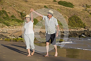 Lovely senior mature couple on their 60s or 70s retired walking happy and relaxed on beach sea shore in romantic aging together